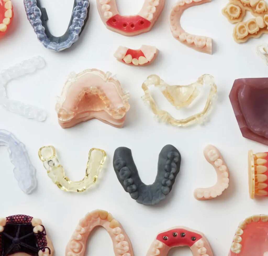 Ποικιλία οδοντικών προθέσεων και μοντέλων που δημιουργούνται με 3D εκτύπωση για την ακρίβεια της θεραπείας.