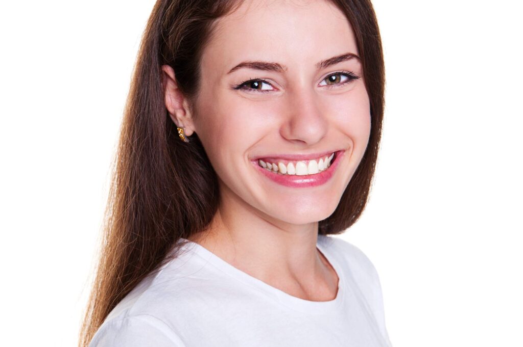 Η γυναίκα δείχνει φυσικό χαμόγελο, αποτέλεσμα της φθορίωσης και της έγκαιρης προληπτικής οδοντιατρικής.