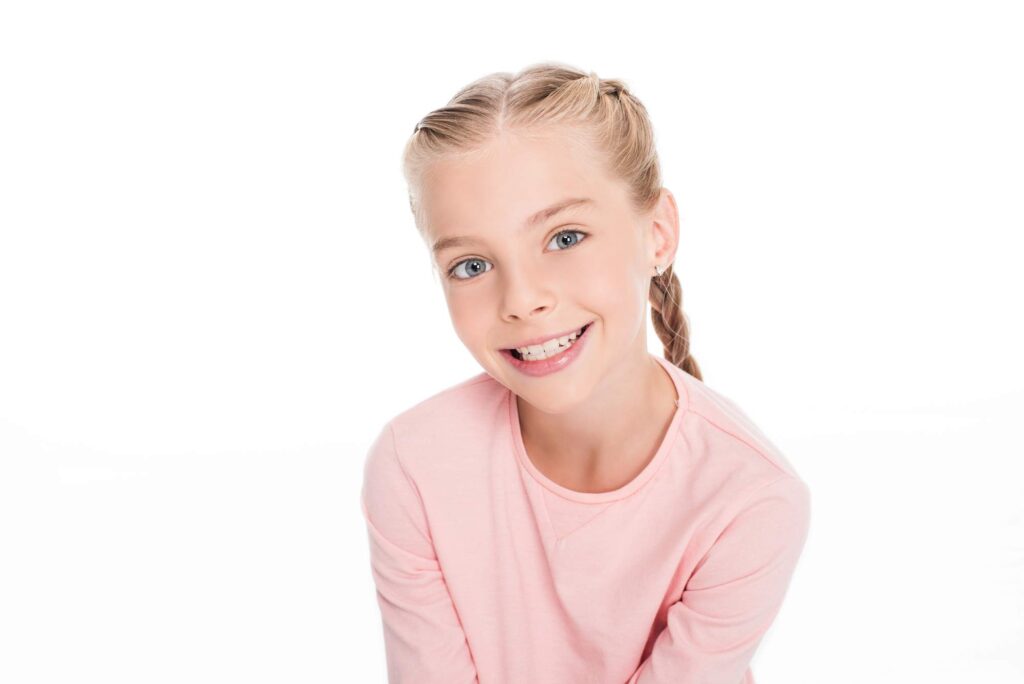 Το κορίτσι δείχνει υγιή δόντια, το αποτέλεσμα της παιδοδοντικής και της παρακολούθησης ανάπτυξης.