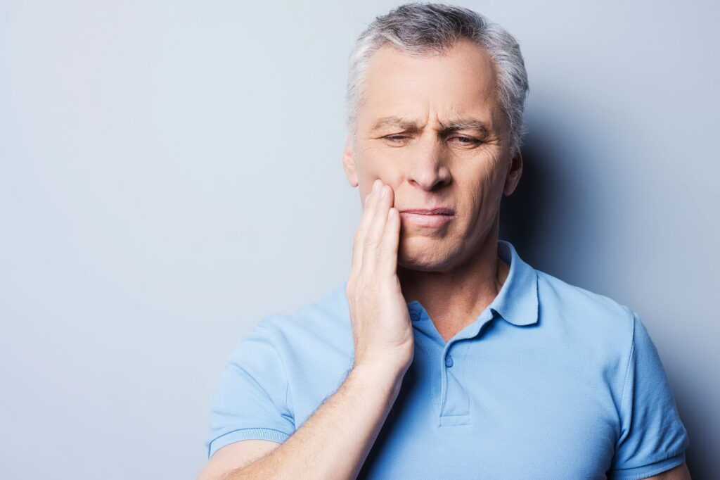 Ο άντρας δείχνει πόνο που μπορεί να είναι μια από τις παρενέργειες εμφυτευμάτων μετά την τοποθέτηση.